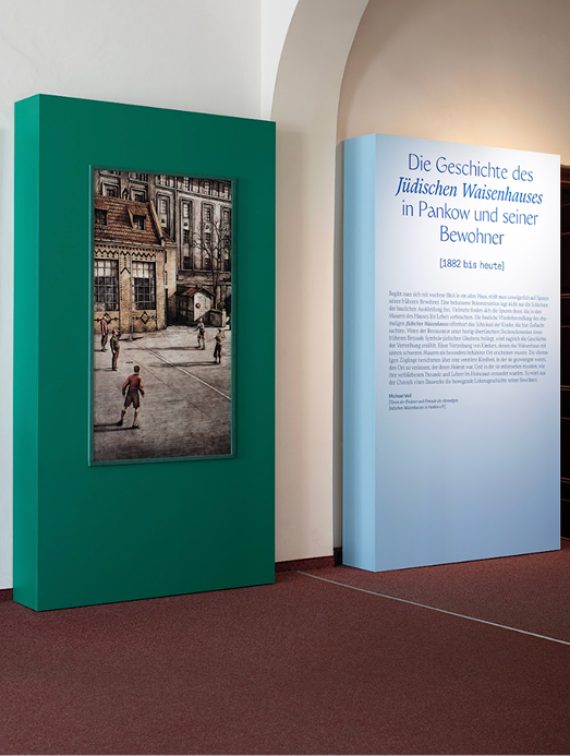 Bildschirmfoto 2026-04-20 um 152054 1 - Waisenhaus Pankow Gemälde in einem Ausstellungsraum, umgeben von grünen und blauen Wänden, mit erläuterndem Text daneben.