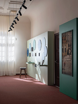 Bildschirmfoto 2026-04-20 um 152130 1 - Waisenhaus Pankow Heller Raum mit Wänden, die runde Spiegel und Informationstafeln zeigen, sowie einem Tisch und einem Hocker.