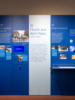 Bildschirmfoto 2026-04-20 um 152213 1 - Waisenhaus Pankow Informationstafel in blauer Wandgestaltung mit Texten zu Flucht aus dem Haus und Kindtransporten, ausgestellt in einem Mus...