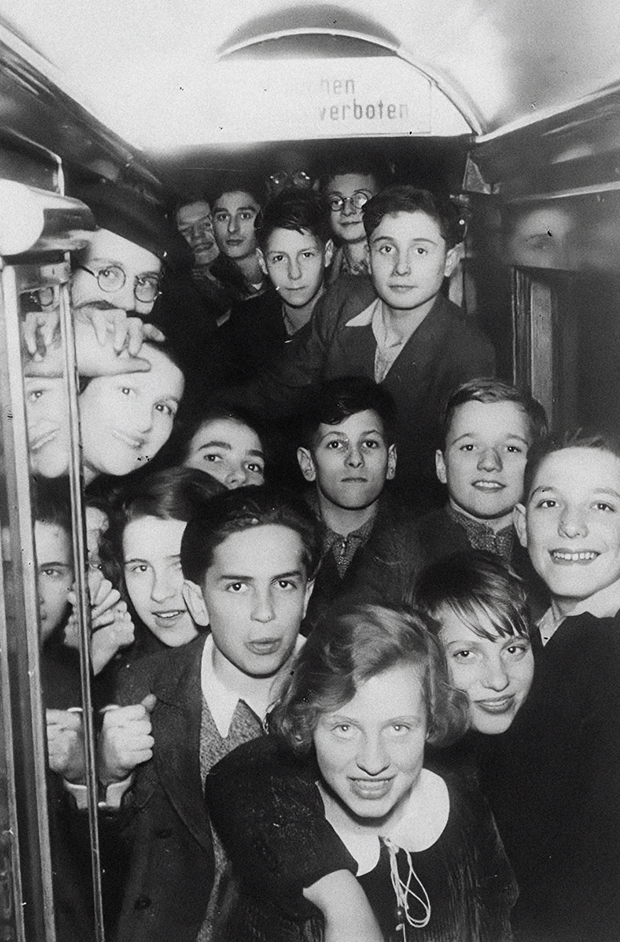 Im Eisenbahnwagen auf dem Kindertransport nach England am 1. Dezember 1938. - Waisenhaus Pankow Eine Gruppe von Jungen und Mädchen posiert in einem engen Raum, vermutlich in einem Zug oder Bus, mit fröhlichen Gesicht...