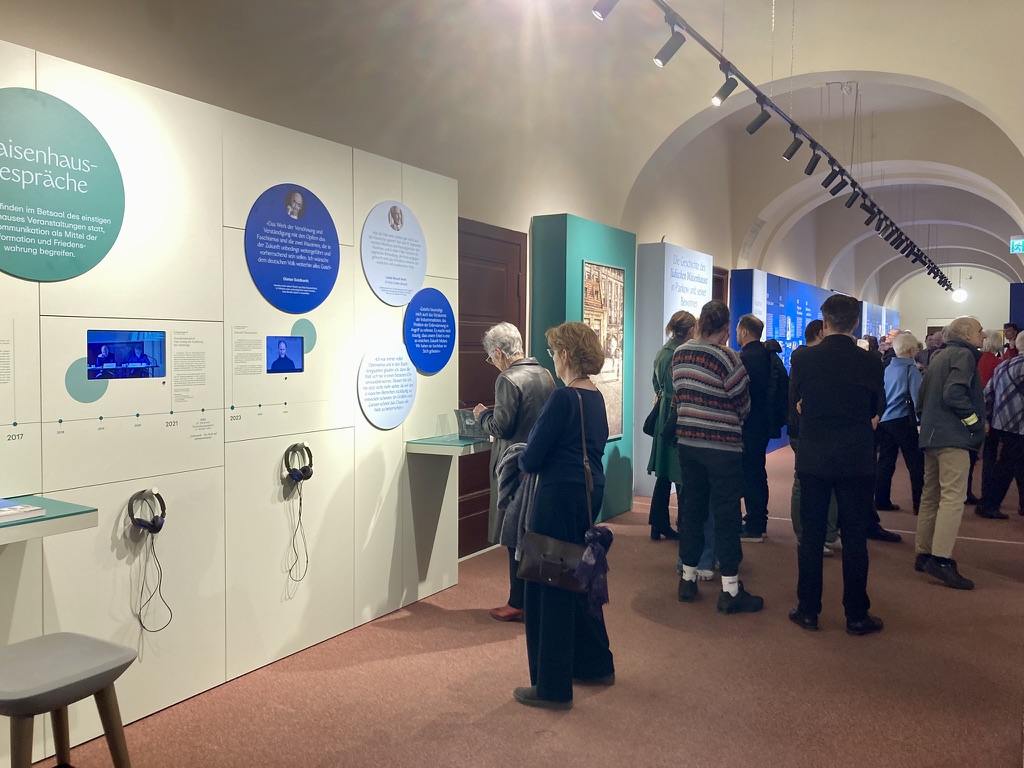 Ausstellung Geführte Gruppen - Waisenhaus Pankow Besucher einer Ausstellung stehen vor interaktiven Displays und Informationswänden in einem hellen, geräumigen Raum.
